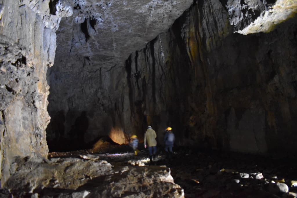three figures walking into a dark cave