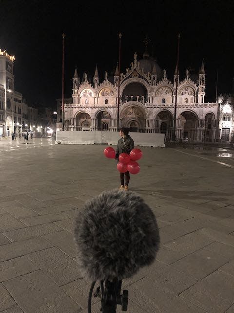 holding balloons at night with microphone in San Marco Square, Venice